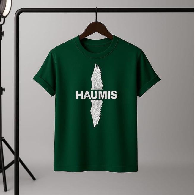 Haumis Emerald Wing Tee hanging on a rack, showcasing the deep emerald color and prominent HAUMIS logo with a wing design.