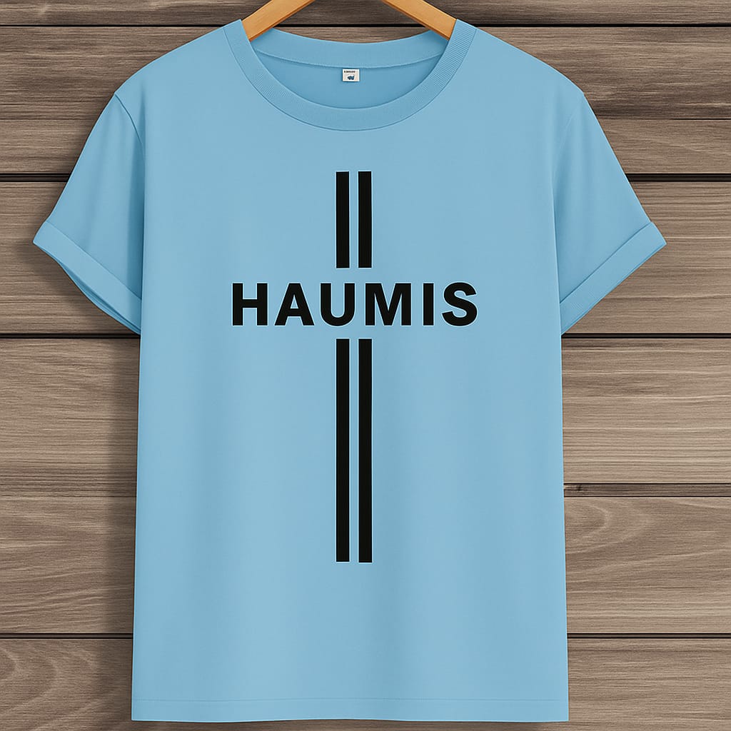 HAUMIS Sand Stripe T-Shirt in light blue color on a wooden background, showcasing its minimalist design with bold black text.