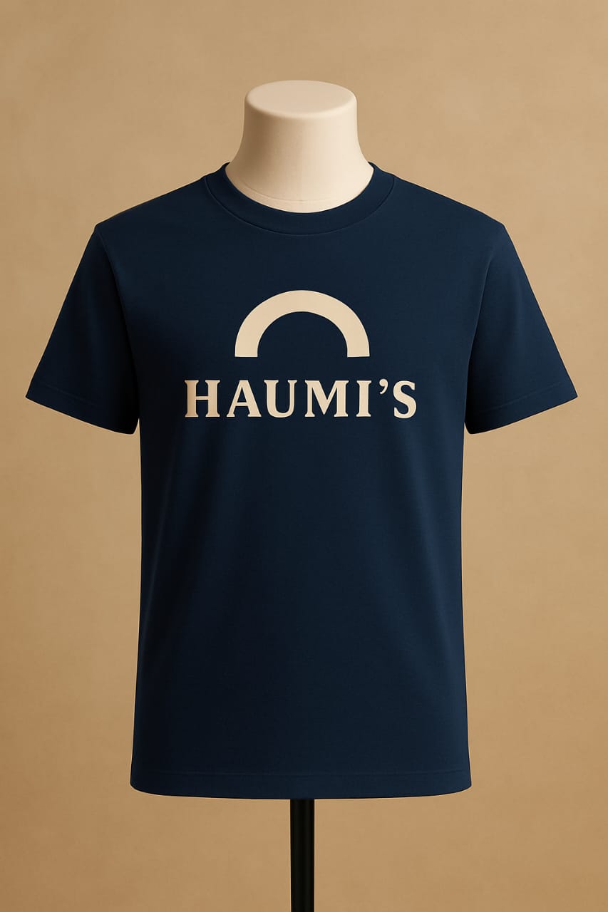 HAUMI’S Legacy Tee – Sandmark Edition in navy blue displayed on a mannequin with a soft beige background, prominently featuring the simple arch logo.