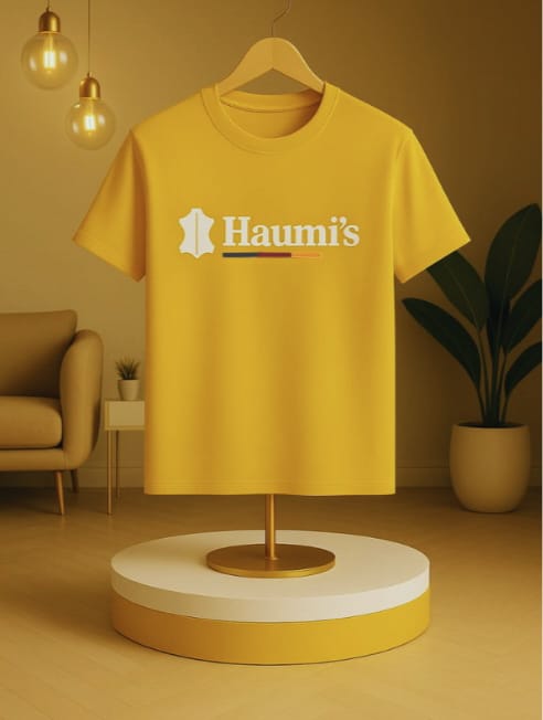 Haumi's Emblem Tee – Earthline Edition in Golden Mustard color, displayed on a wooden hanger, showcasing minimalist design and front logo print.